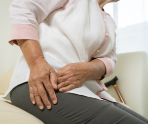 Woman sitting down while holding hip due to pain